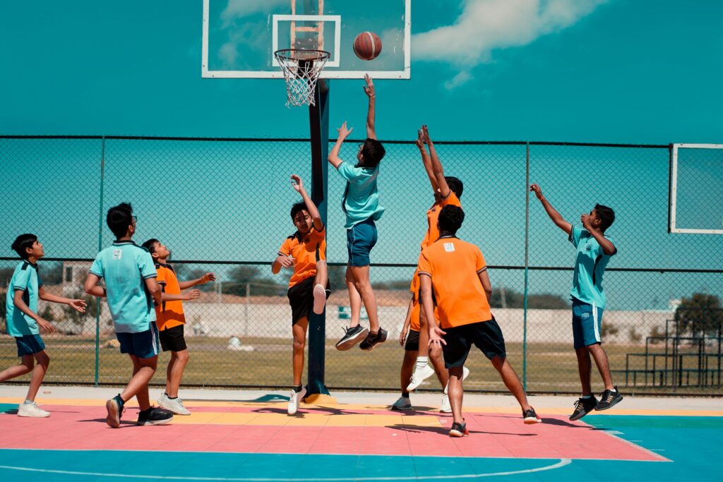 Group of teenagers playing basketball energetically on a colorful outdoor court.
